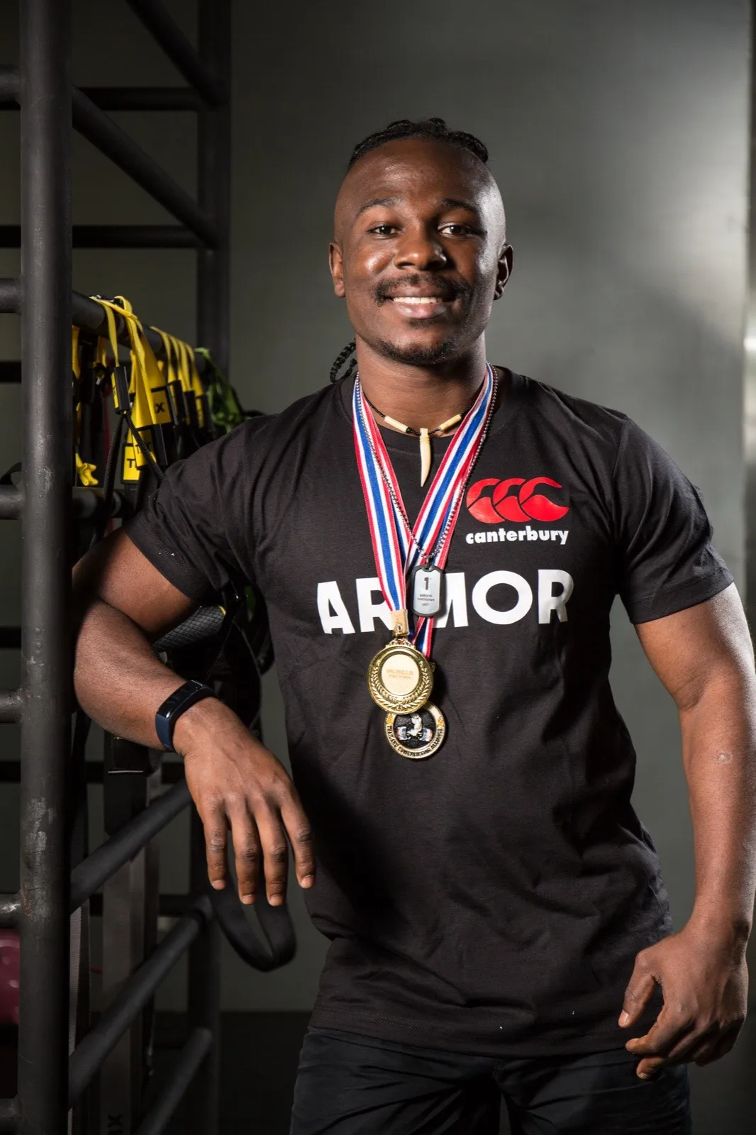 Coach Patient, founder of Rhino Fitness, wearing competition medals