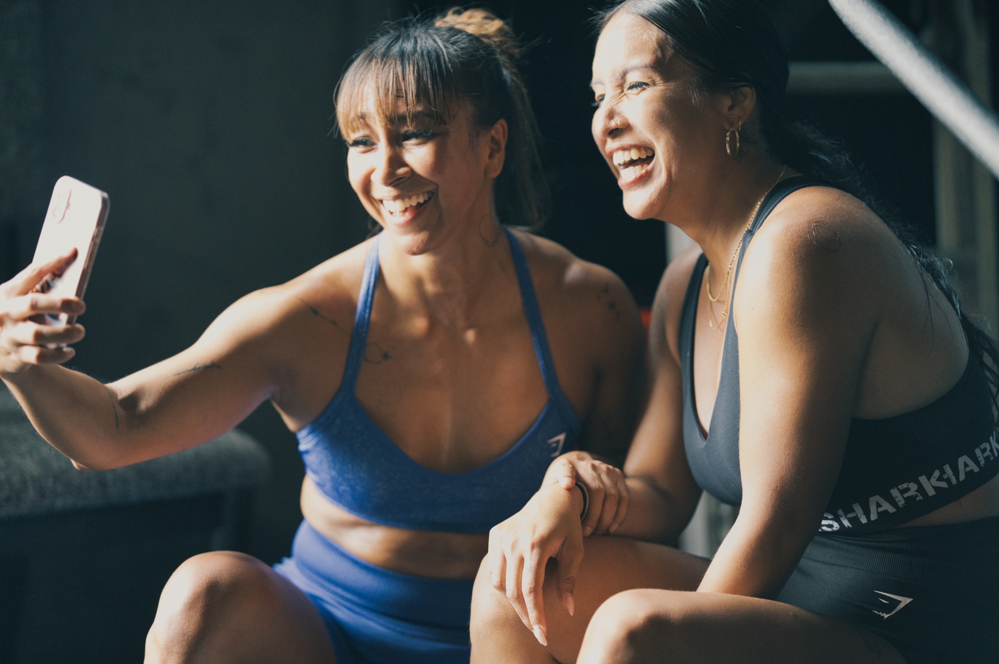 Two Rhino Fitness members smiling while taking a selfie with their phone